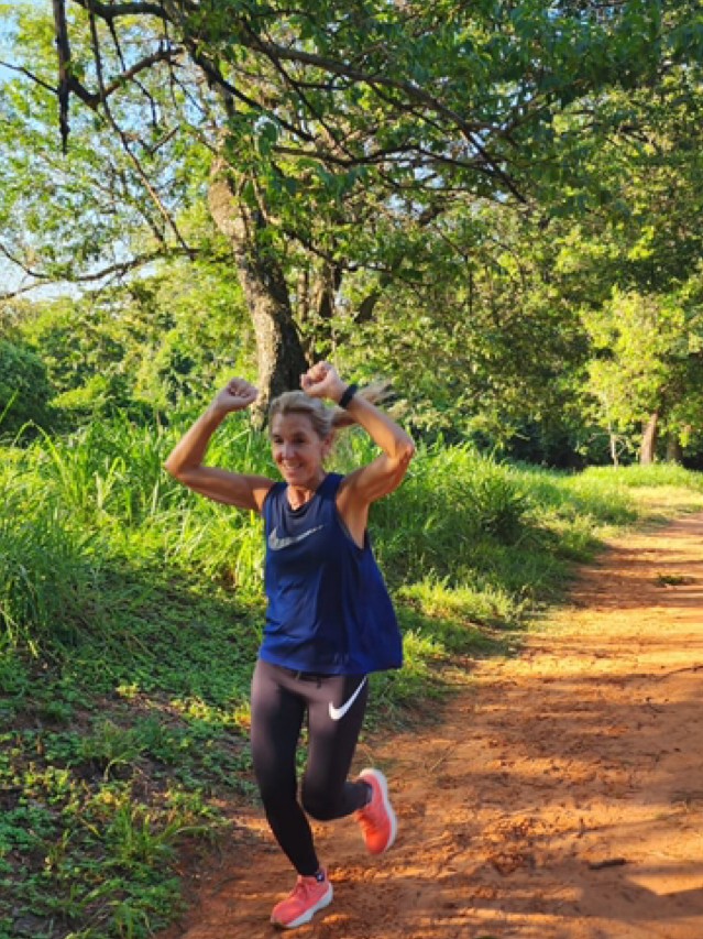 Eve Caniza corriendo por un sendero y celebrando con los brazos en alto