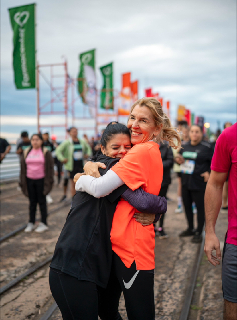 Dos mujeres se abrazan sonriendo al terminar una carrera inclusiva