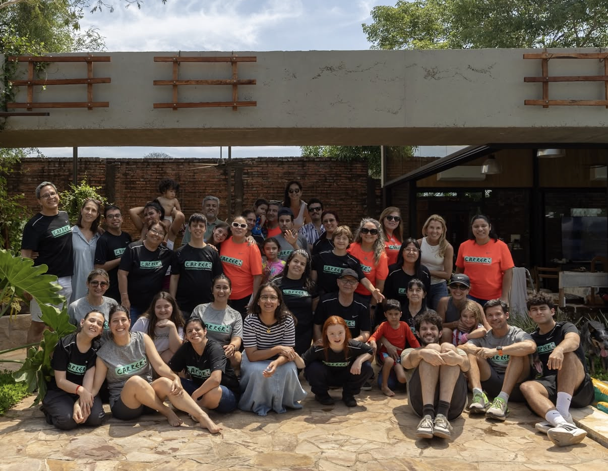Grupo de participantes de una carrera inclusiva posando juntos, con camisetas que dicen «Carrera»